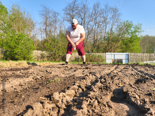 Φωτογραφία Man gardening outdoors on a sunny day, preparing fertile soil and hand-seeding rows in his home vegetable garden for future harvest, sustainable homegrown food