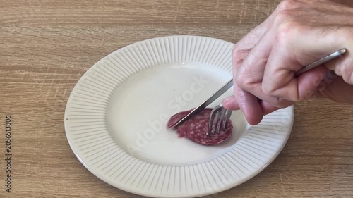 steel fork and knife screeching and scraping when cutting sausage on ceramic plate