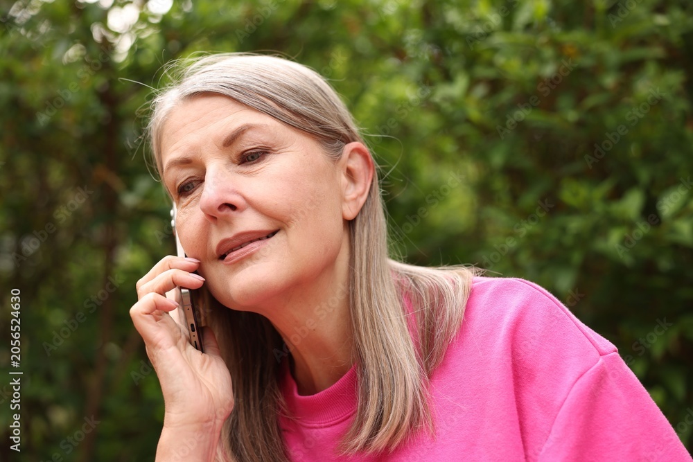 Fototapeta premium Beautiful senior woman talking on phone in spring park