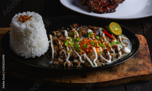 Cuadro en lienzo close up photo of spicy sizzling sisig pork mask meal with fried rice, egg and mayonaise on top on a sizzling plate