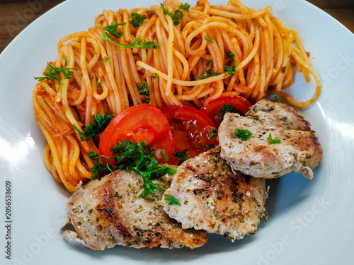 Spagetti mit gebratenen Schweinemedaillons garniert mit Tomate und Petersilie