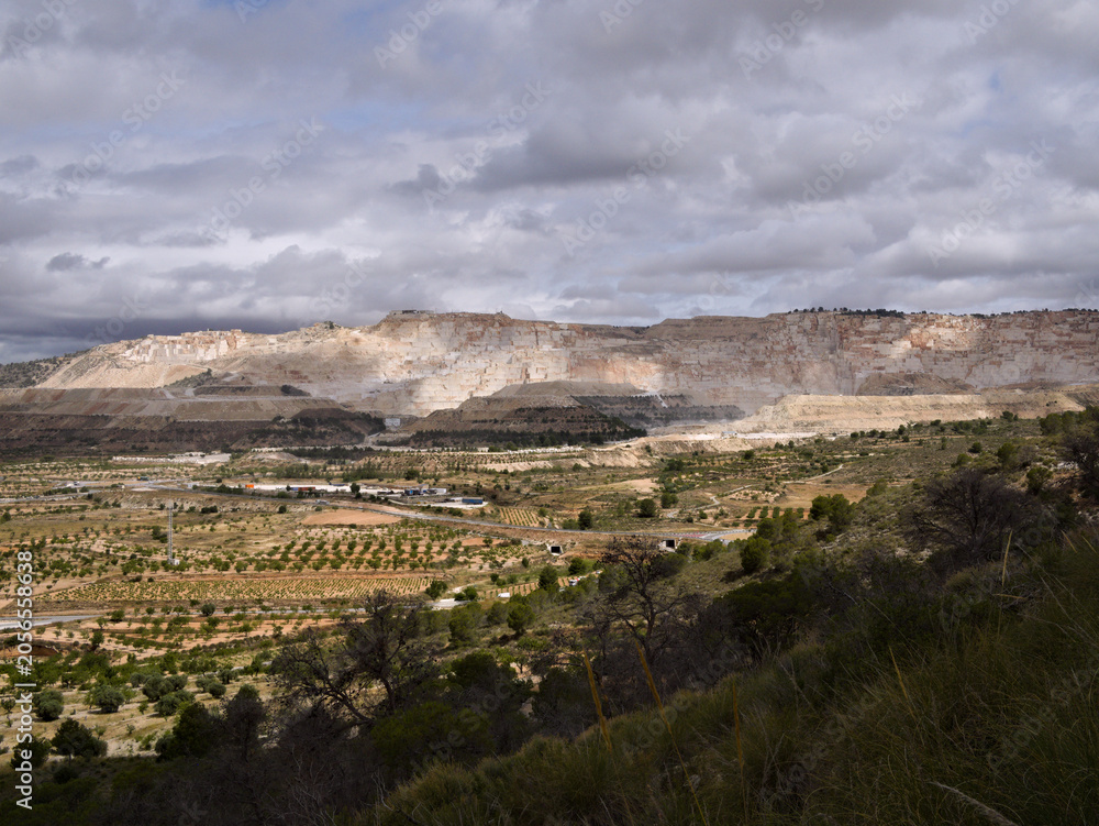 Obraz premium Marble quarry exposed to rays of sunlight on a cloudy day in Alguena, Spain
