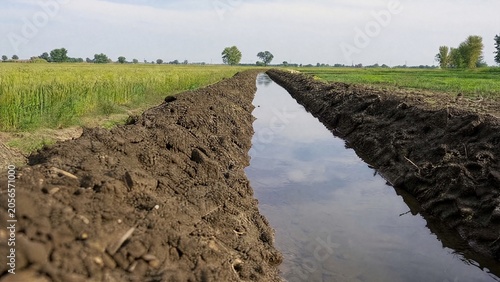 Foto Freshly dug irrigation ditch with moist soil banks in farmland.
