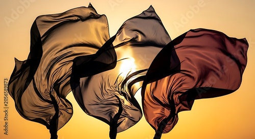 Three Flowing Translucent Flags Backlit by Sunset Sky