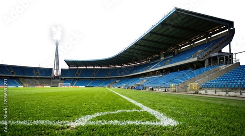 Empty football stadium with blue seats and green grass pitch