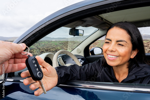 Fotografie Happy woman smiling, accepting a car key from an outstretched hand, ready for a