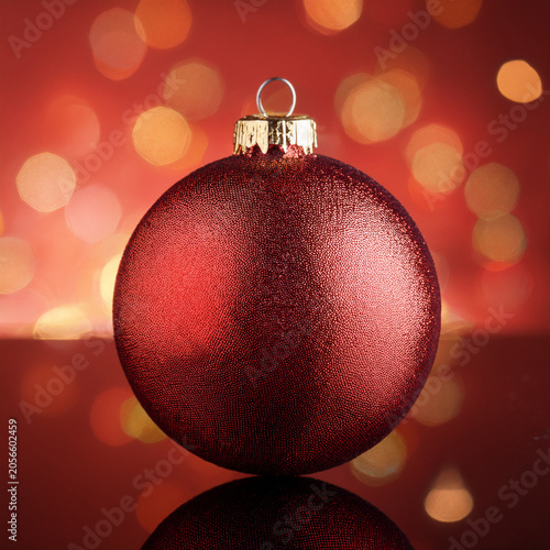 Red christmas ornament reflecting on festive bokeh background