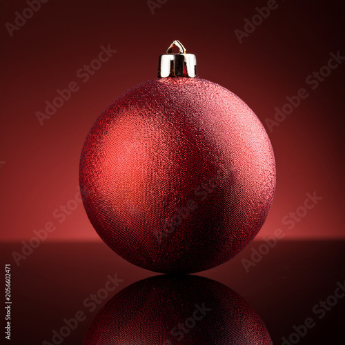 Red christmas ornament reflecting on dark surface