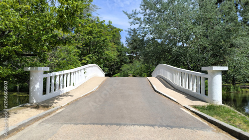 Canvastavla Symmetrical White Arched Park Bridge with Balustrade Railings Leading Into Green