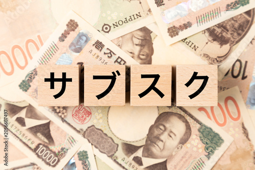 「サブスク」と書かれたブロックとたくさんの一万円札