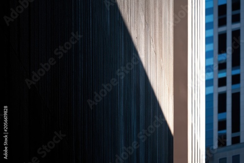 Stark diagonal shadow on a modern building facade, blue sky and windows beyond