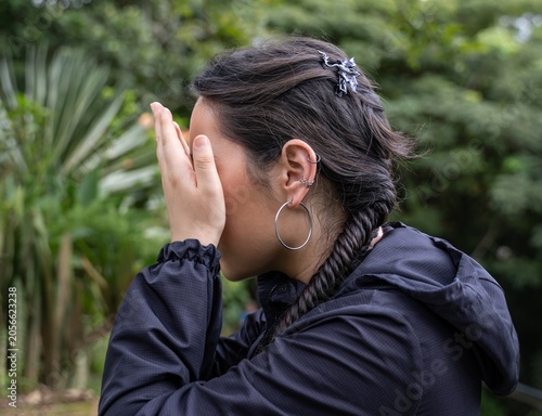 Obraz na plátne Profile view of a woman covering her face with her hands outdoors