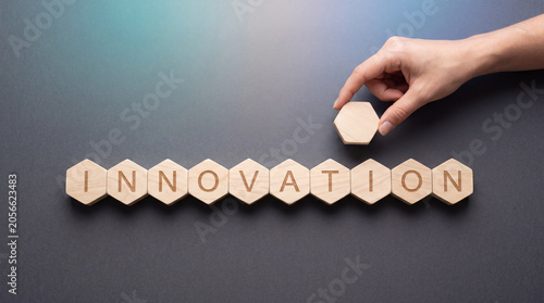 Business innovation and technology concept with hexagonal wooden blocks spelling INNOVATION on a dark background with hand touch and copy space