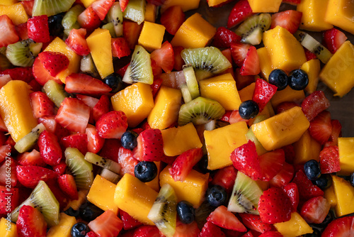 Vista superior de una macedonia de frutas cortadas con fresas, mango, kiwis y arándanos