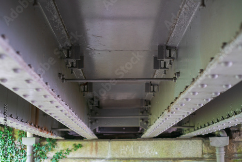 Underside view of riveted steel bridge girder structure and metal bracing elements