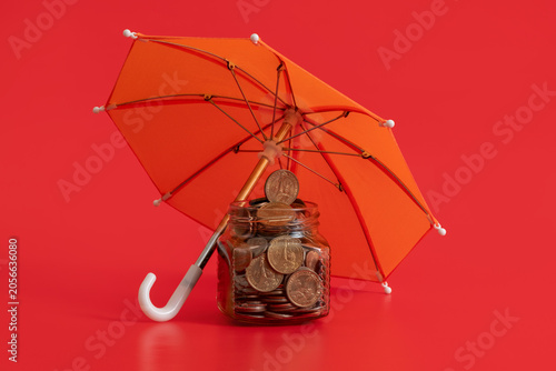 Foto US coins in a glass jar protected by an umbrella on a red background