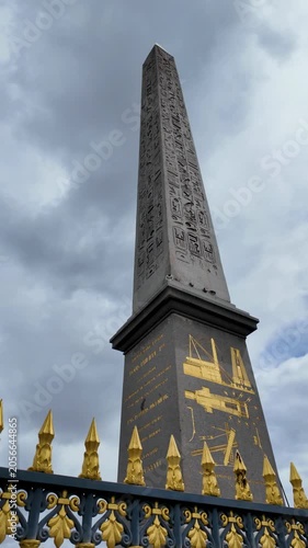 Ancient Egyptian obelisk with gold hieroglyphics standing in Place de la Concorde under cloudy sky
