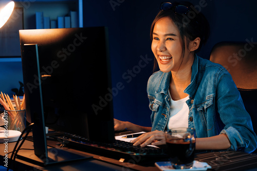 Billede på lærred Successful young beautiful asian creative looking digit of profit on pc with sales target calculating report, earning job's freelancer for planning profitable strategy at neon light night