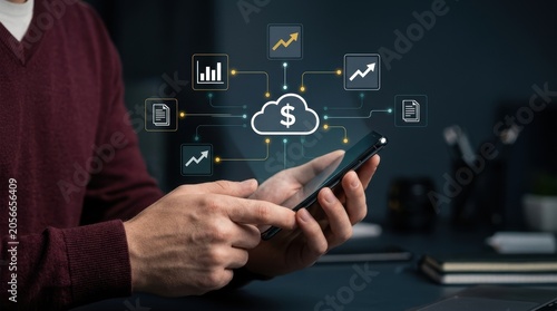 Professional using smartphone displaying glowing cloud financial icons and growth charts over office desk, fintech analytics, cloud accounting, digital wealth modern technology business concept