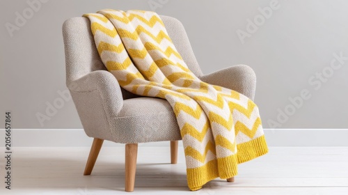 A classic Scandi lounge chair upholstered in a thick woven fabric with a large scale charcoal and cream chevron pattern, a yellow knitted throw over
