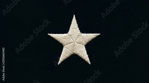 A detailed, textured white star embroidered on a dark fabric background, creating a striking contrast.