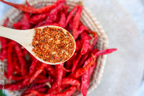 Foto ​Spicy red chili powder on wooden spoon with dried red chilies in basket