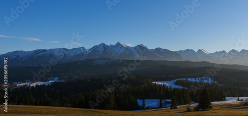 Majestic Tatra mountains landscape covered with snow in winter. Panoramic view of snowy rocky peaks against blue sky