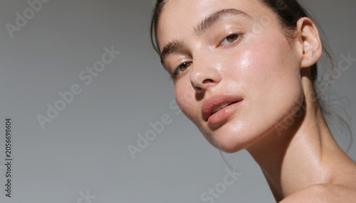 Woman's radiant face with natural glow during soft studio lighting and selective focus for skincare advertising
