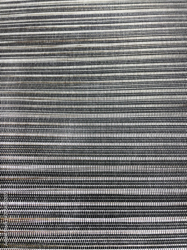 Close-up of a woven striped textile texture in black, white and gray tones. Modern fabric pattern with fine threads and linear design, ideal as a background for decor, textiles and design.