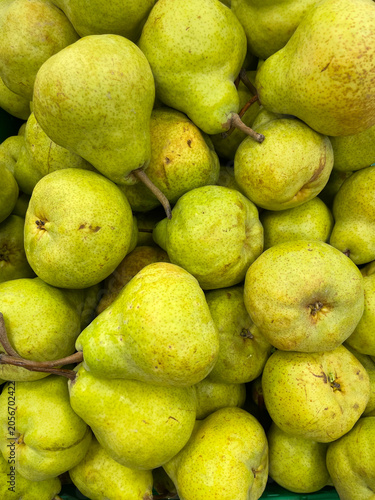 Fresh green pears piled together at a local market. Ripe, juicy fruits with natural texture create a healthy food background, perfect for agriculture, grocery, harvest, nutrition and seasonal themes.