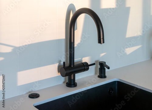 Photos Matte black kitchen faucet with built-in soap dispenser and garbage disposal button over a black undermount sink
