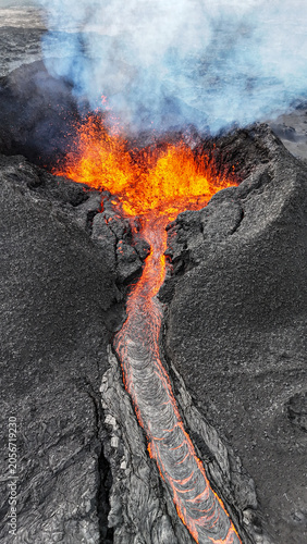 Lava fountain feeding a glowing lava channel during eruption in Iceland
