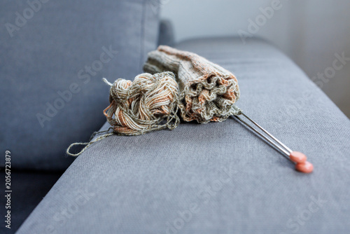 Foto Partially completed knitted project with yarn on sofa armrest
