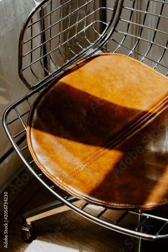 Brown leather chair with chrome wire frame in warm sunlight,