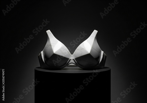 Modern marble bra sculpture displayed on a dark pedestal against a black background