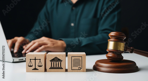 Justice on Screen: A close-up shot depicts a gavel on a desk beside three wooden blocks with icons representing justice, government, and law, as a person works on a laptop in the background.