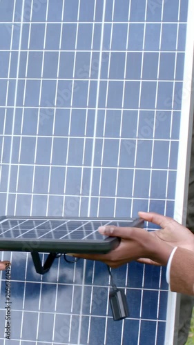 Vertical video: Rubbing solar panel, tan longsleeve man handing small module for demo on grass