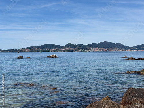 Fotografie Calm coastal waters with mountain backdrop at Samil Beach in Vigo Galicia Spain
