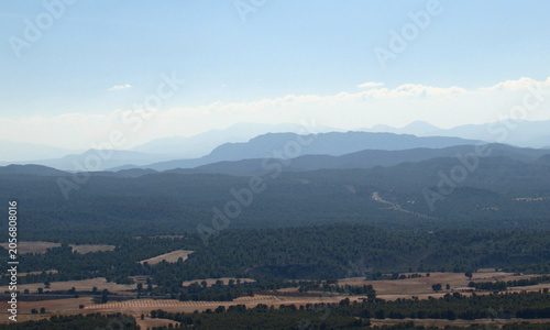 Panoramic view of layered mountain ridges fading into the hazy distant horizon under a clear sky.