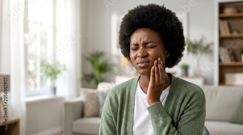 Attractive African woman holding jaw experiencing severe toothache and dental pain