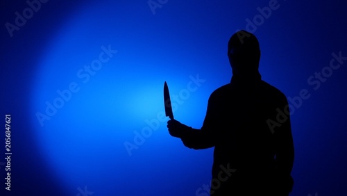 Εκτύπωση καμβά Silhouette of a mysterious person holding a large kitchen knife, creating a chil