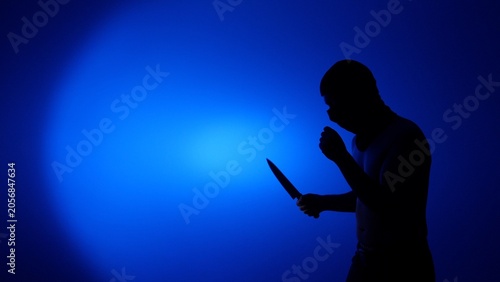 Canvastavla Silhouette of an unrecognizable masked man holding a knife, representing crime,