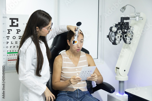 Foto Professional optometrist performing a computerized eye examination while assisti