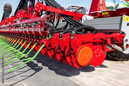 Fotografie Close-up view of a large red farm cultivator parked on a concrete yard, showing