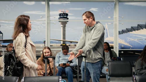 Fotografia Scolding man, bumping trolley and upset woman in airport hurrying to catch plane, Yelling, bashing luggage and angry tourist with traveler in busy departure terminal, camera A with hectic and crowd
