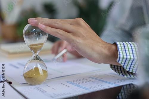 Foto Close up of hand on sandglass for deadline and time management concept