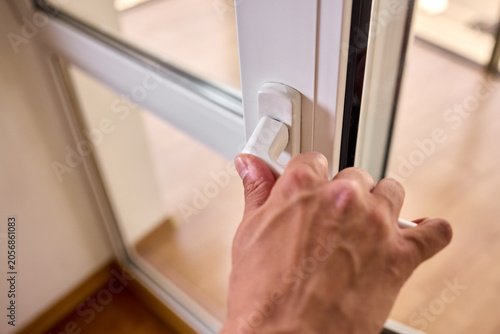 Foto Hand adjusting a white window security latch on a wooden frame