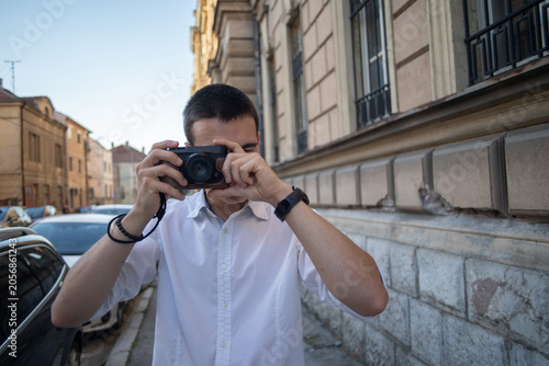 Foto A young man holding a retro camera and taking photos in the city