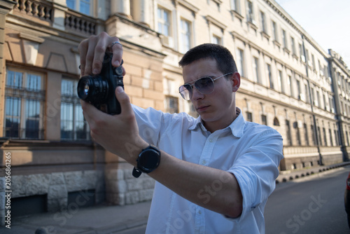 Foto A young man holding a retro camera and taking photos in the city