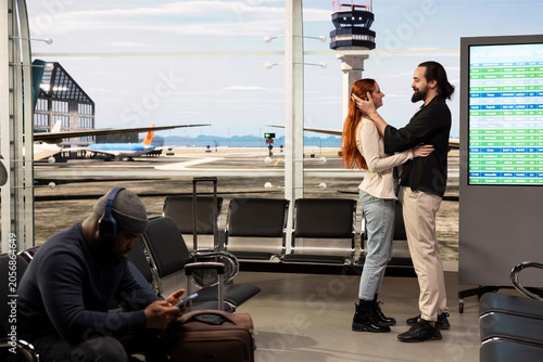Foto Young couple reuniting in airport terminal after long-distance relationship, hugging with joy upon arrival, man and woman sharing emotional heartwarming moment near runway